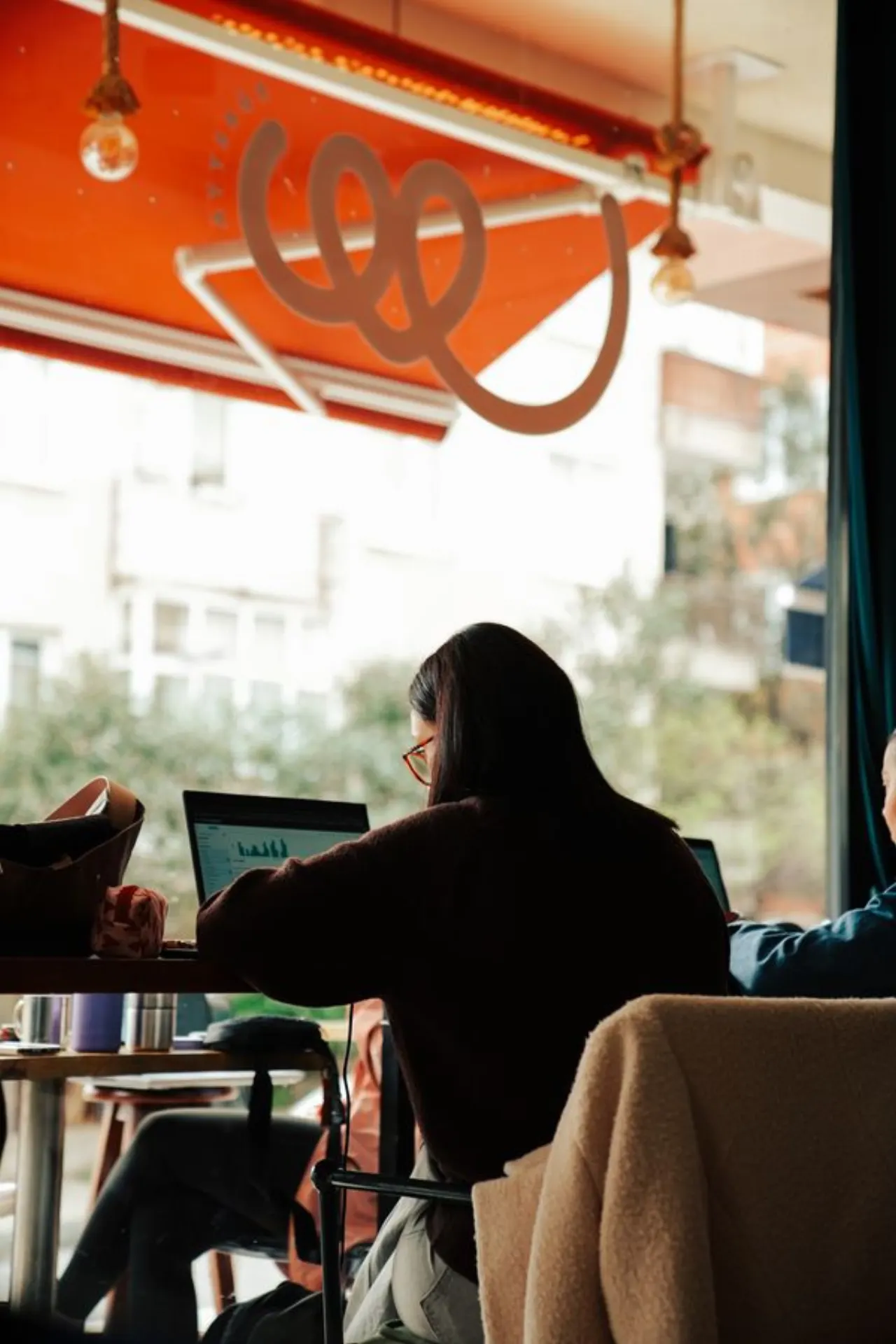 Người làm việc bên laptop tại quán cà phê